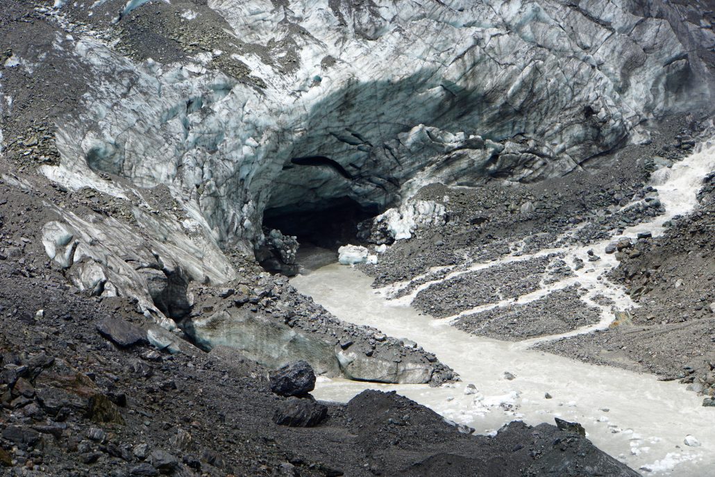 Utloppet under Fox Glacier. Grus och sten samlas ovanpå isen.